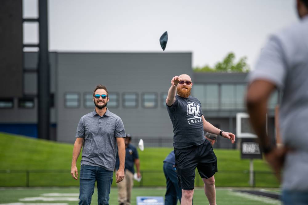 Man underhand tossing a cornhole bag into the air